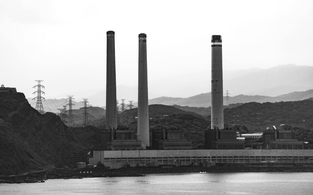Black and white photo of a large industrial power plant in Taiwan with smoke stacks against a mountainous backdrop.