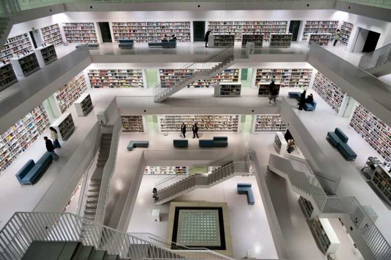 A spacious, contemporary library with minimalist architecture and bookshelves on multiple levels.